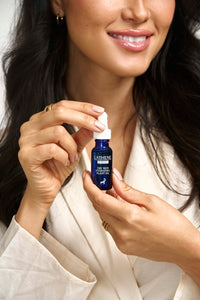Smiling woman holding a bottle of L'ATHENE EXTRACT Dry Skin Hydrating Plant Oil, showcasing its use.