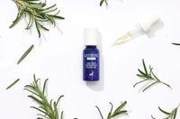 L'ATHENE EXTRACT Dry Skin Hydrating Plant Oil in blue bottle with dropper, surrounded by rosemary sprigs on white background.